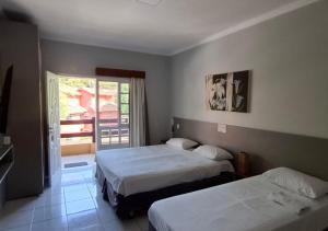 a hotel room with two beds and a balcony at Flat Incrível Amarilis dentro da Riviera São Lourenço - 2 Unidades disponíveis, Duplex 2 Quartos, Cozinha e Varanda ou Unidade tipo Estúdio sem Cozinha in Riviera de São Lourenço +77 photos