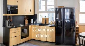 a kitchen with a black refrigerator in a room at Ômarais Guest House in Paris