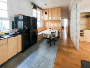 a kitchen with a table and a black refrigerator at Ômarais Guest House in Paris