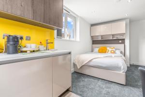 a bedroom with a bed and a yellow accent wall at Contemporary Comfort Steps from Ricoh Arena in Coventry