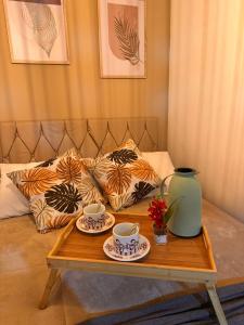 a coffee table with two cups and a vase on it at My Yellow House Casal in Campos do Jordão