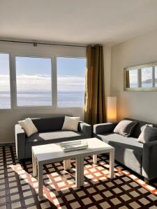 ein Wohnzimmer mit zwei Sofas und einem Tisch in der Unterkunft Duplex B Vacaciones en el mar in Ribeira