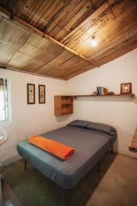 Dormitorio con cama con almohada naranja en Casa blanca, Refugio Natural Jacaranda, en Cocorná