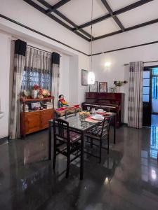 a dining room with a table and a piano at Serenity Home Stay in Kandy