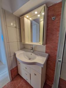 a bathroom with a white sink and a mirror at Poseidon's Balcony by Infinity in Nea Kalikratia