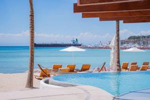 - une piscine sur la plage avec des chaises et des parasols dans l'établissement Condo Cortes Y Club De Playa La Paz, à La Paz