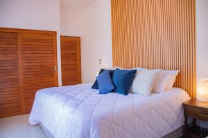 une chambre avec un grand lit blanc avec des oreillers bleus dans l'établissement Condo Cortes Y Club De Playa La Paz, à La Paz 10 autres photos