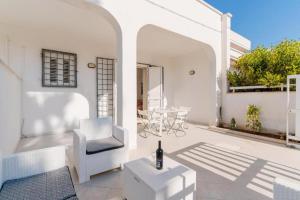 a white patio with a chair and a table at Villino Airone in Torre Lapillo