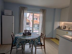 a kitchen with a table with chairs and a refrigerator at T2 na Praia da Costa Nova com Varanda - Yellow Door in Costa Nova