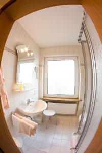 ein weißes Bad mit einem Waschbecken und einem Fenster in der Unterkunft Hotel Restaurant Krone in Nassau