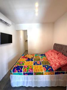 Una cama en una habitación con una colcha colorida. en Suíte 8 - Village Capixaba, en Gravatá