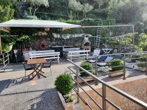 a patio with benches and a table and an umbrella at Apartments and rooms Roberto B. in Valun
