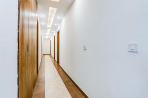 un corridoio con pareti bianche e un lungo corridoio con porte in legno di Hotel O The Grand Blue Hotel a Noida
