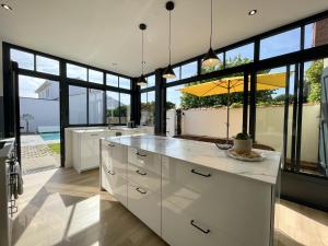 een keuken met witte kasten en grote ramen bij Villa Georgette in Saint-Gilles-Croix-de-Vie