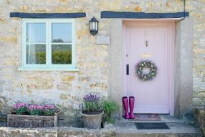 a front door of a stone house with a wreath and boots at 18th Century Thatched Cottage Parking & Garden in Beaminster