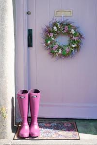 ein Paar rosa Gummistiefel vor einer Tür in der Unterkunft 18th Century Thatched Cottage Parking & Garden in Beaminster