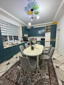 a kitchen with a table and chairs and blue cabinets at Гостевой дом in Aralʼsk