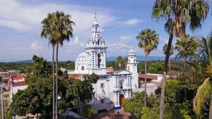 a white church with a tower and palm trees at Hospedaje la gran Tenochtitlán in San Martín Hidalgo