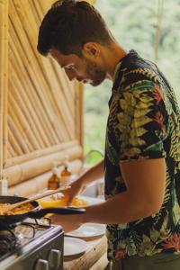 a man standing in a kitchen preparing food at Ecocabaña Pocahontas en rio Santo Domingo, Melcocho in Cocorná