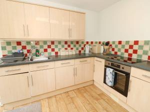 una cocina con armarios blancos y azulejos verdes y blancos en Swifts, en Ventnor 20 fotos más