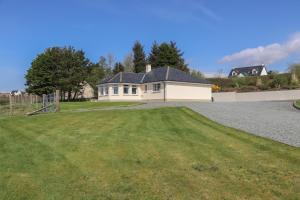 a house with a large yard in front of a driveway at Riverside Cottage in Portree