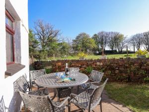 Un patio con mesa y sillas y una valla. en Kernyk, en Camelford