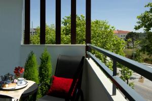 - un balcon avec une table et un oreiller rouge dans l'établissement Hotel Lagoa dos Pastorinhos, à Fátima
