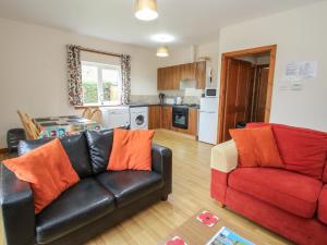 un soggiorno con divano in pelle nera e cuscini arancioni di Cooinda Cottage a Morar Altre 12 foto