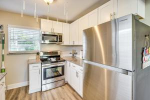 a kitchen with white cabinets and a stainless steel refrigerator at 4 Mi to Daytona Boardwalk and Beaches Cute Cottage in Holly Hill +16 photos