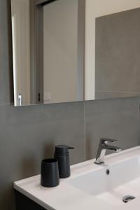 a bathroom sink with two black cups on it at B&B Bdieci in Valguarnera Caropepe
