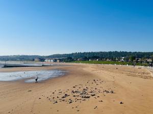 a person walking on a beach with rocks at The Magnolia in Rhos-on-Sea