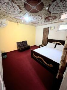 een slaapkamer met een bed en een bank erin bij Dream Guest House, Skardu in Skardu