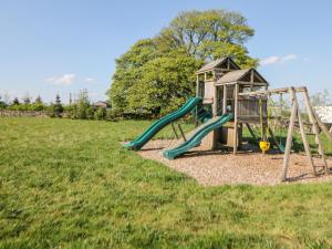 Un parque infantil con un tobogán y una estructura de juego. en The Coach House at Mayfurlong Farm, en Leek