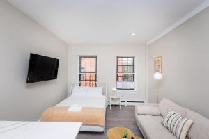a white bedroom with a bed and a couch at Newly Renovated w Exposed Brick in Boston