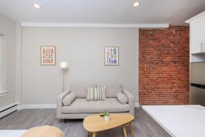 a living room with a couch and a brick wall at Newly Renovated w Exposed Brick in Boston