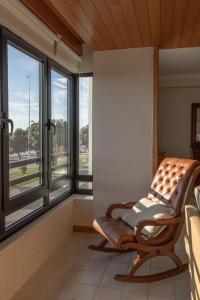 a rocking chair in a room with windows at Vista Atlântica-Vila do Conde in Vila do Conde