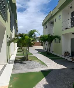 a courtyard with palm trees between two buildings at Residencial Brasil Coroa - Staybeach in Porto Seguro
