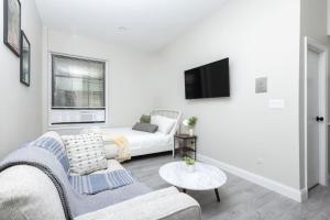 a white living room with a couch and a bed at Charming South End Studio Apt in Boston