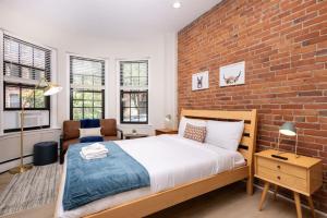 Schlafzimmer mit Ziegelwand und großem Bett in der Unterkunft Serene Studio with Cozy Atmosphere in Boston