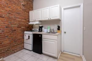 eine Küche mit weißen Schränken und einer Ziegelwand in der Unterkunft Serene Studio with Cozy Atmosphere in Boston