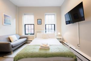 een slaapkamer met een bed, een bank en een televisie bij Bright Modern Studio in the South End in Boston