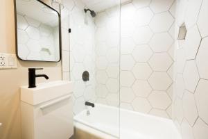 een witte badkamer met een wastafel en een spiegel bij Bright Modern Studio in the South End in Boston