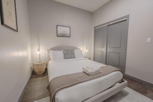 a white bedroom with a large white bed and a door at Elegant 2 Bedroom Prime Location in Boston +8 photos
