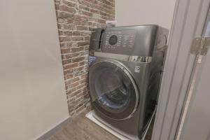 a washing machine in a room with a brick wall at Elegant 2 Bedroom Prime Location in Boston