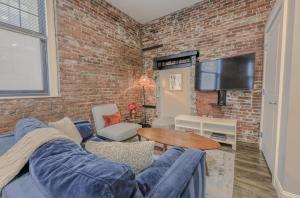 a living room with a blue couch and a brick wall at Unbeatable Location 4 bed Loft Parking Optional in Boston