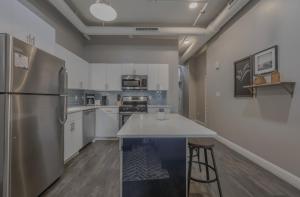 una cocina con nevera de acero inoxidable y armarios blancos en Luxury Furnished Loft near Park Street Station, en Boston 3 fotos más