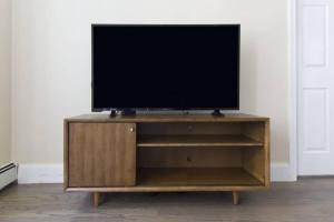 a flat screen tv sitting on top of a wooden entertainment center at Beautiful 2 Bedroom Financial District Apartment in Boston