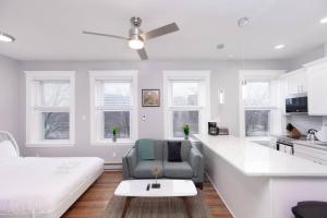 a white living room with a couch and a ceiling fan at Cozy Central Fenway Studio in Boston +1 photo
