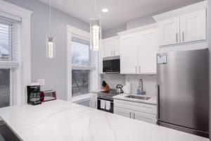 a kitchen with white cabinets and a stainless steel refrigerator at Cozy Central Fenway Studio in Boston