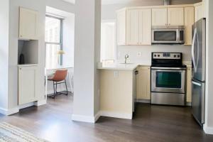 a kitchen with white cabinets and stainless steel appliances at Spacious FIDI 2br 2ba Close to Everything in Boston